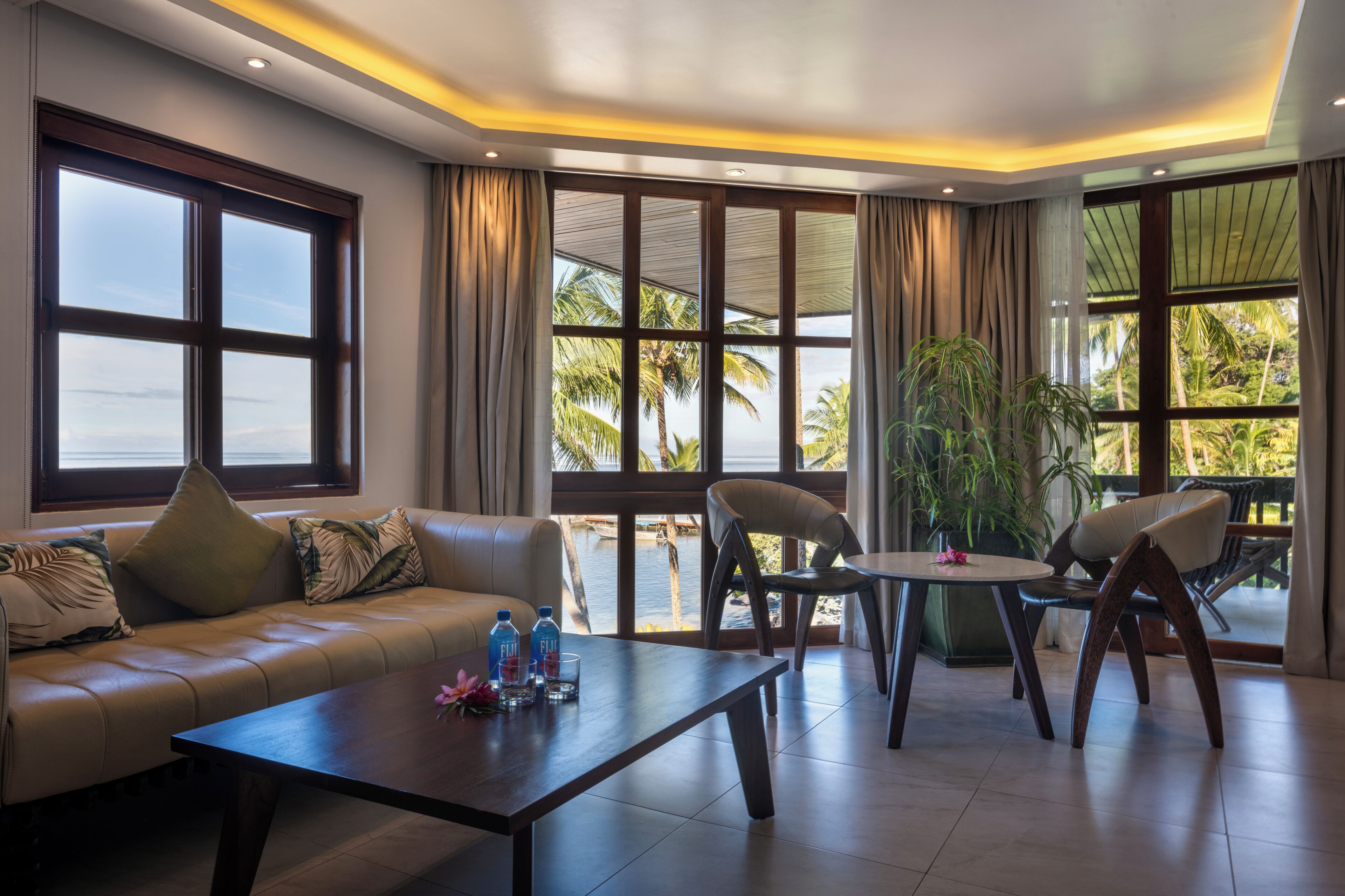 Una habitación de hotel moderna con sofá, mesa de centro y zona de comedor.