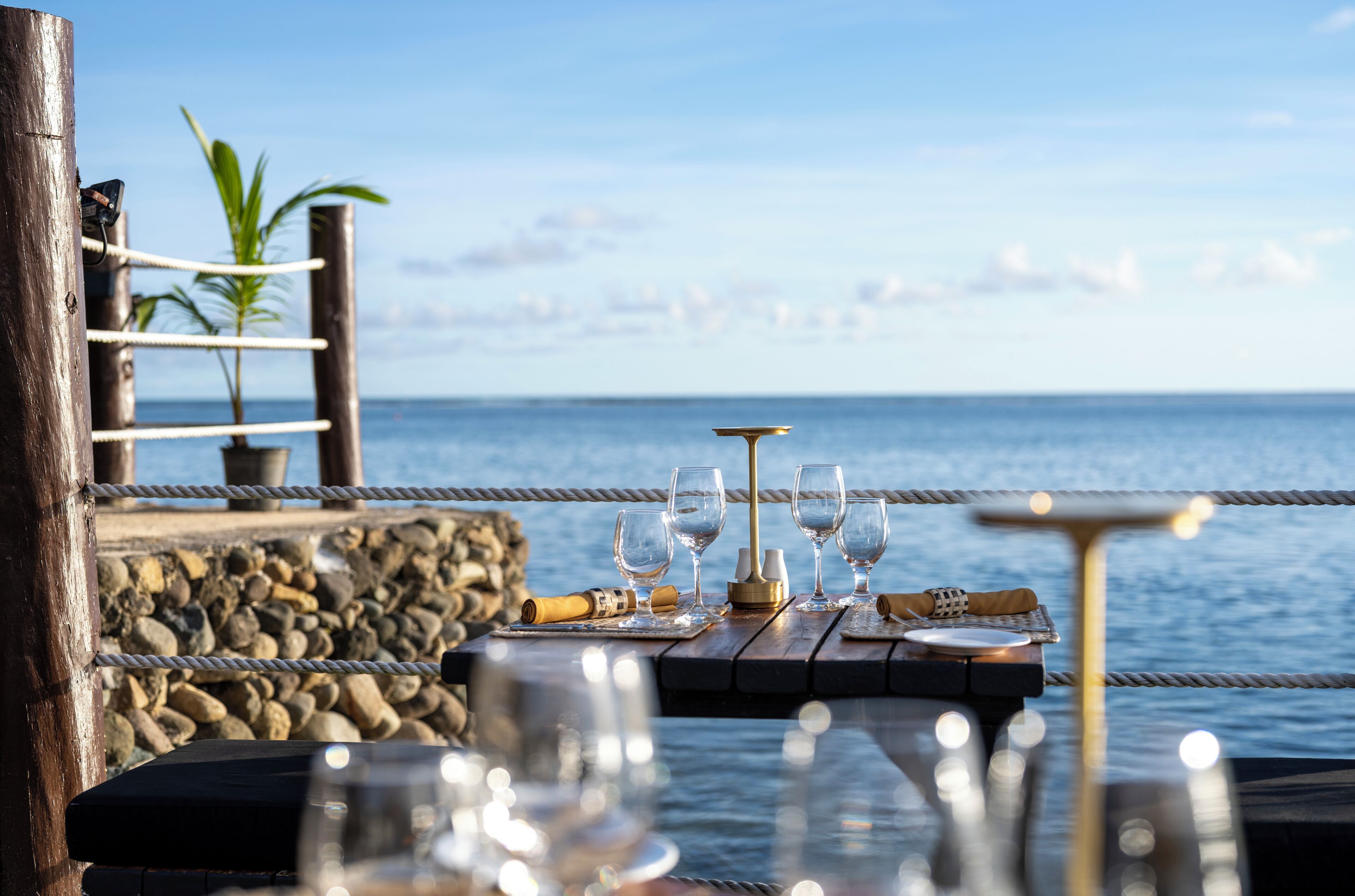 A table set with glasses and a bottle, overlooking the ocean.