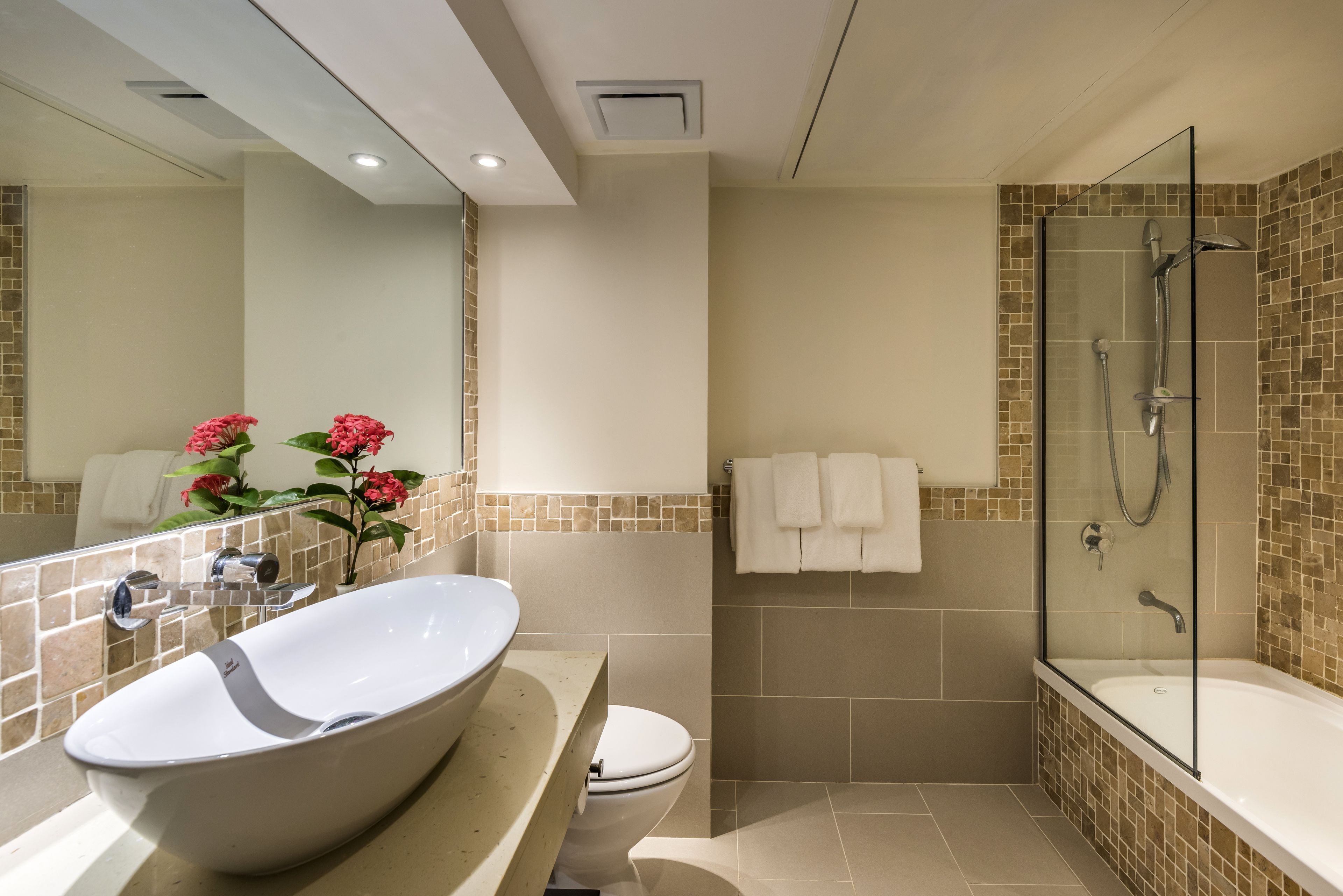 Un baño moderno con una bañera independiente, un lavabo grande y una ducha con mampara de vidrio.