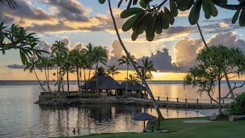 A resort with a pool, palm trees, and a sunset view.