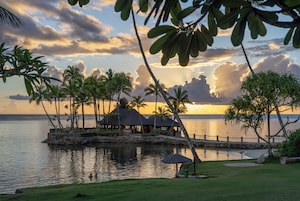 Un resort con piscina, palmeras y vistas al atardecer.