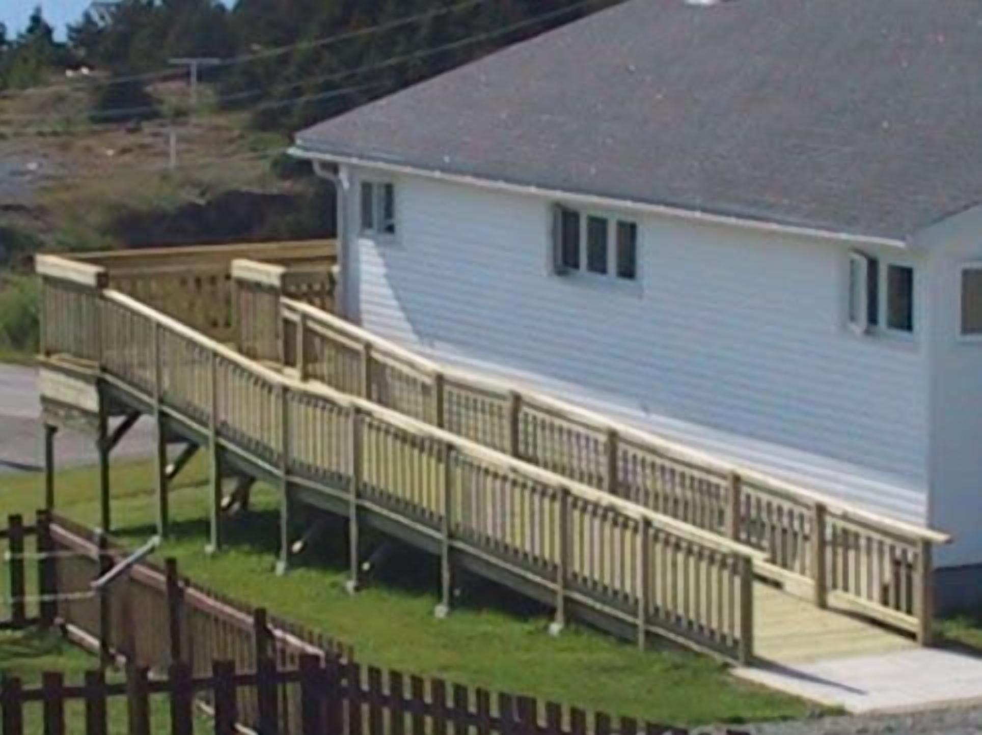 Ein eingeschossiges Haus mit Veranda und Holzterrasse.