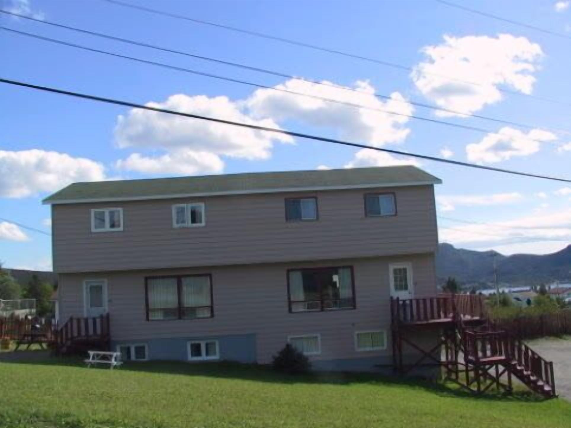 A two-story building with a flat roof, a small porch, and a fenced yard.