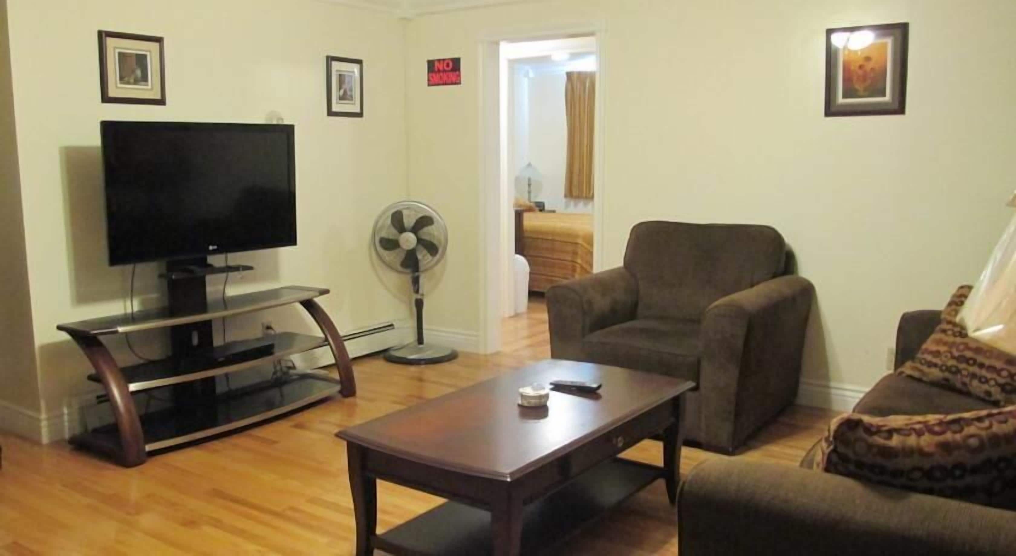 A living room with a TV, a fan, a sofa, and a coffee table.