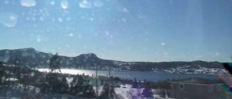 Un paysage enneigé avec un lac, des montagnes et un bâtiment.