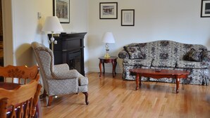 A living room with a patterned sofa, a patterned armchair, a wooden coffee table, and a fireplace.