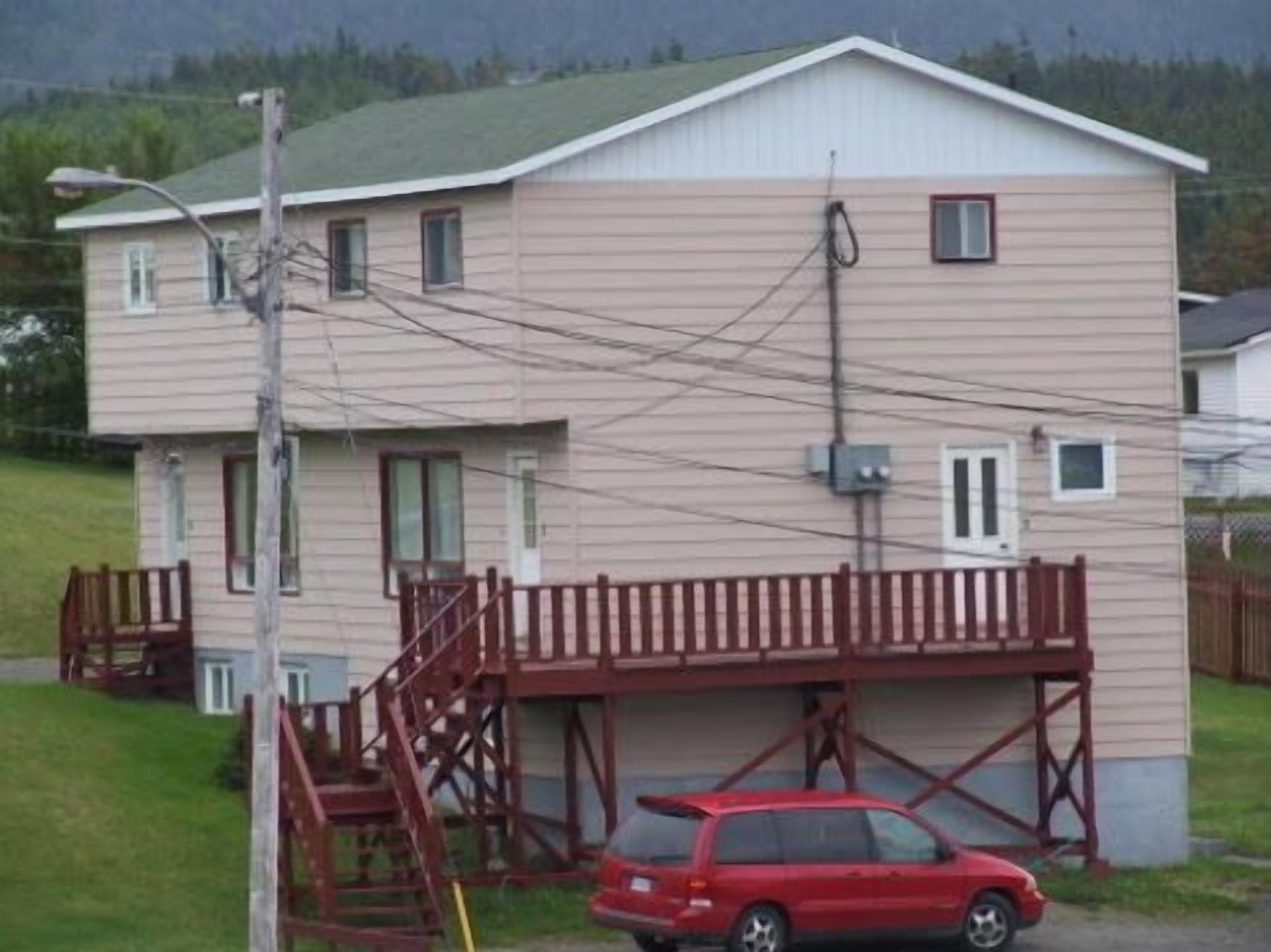 A two-story house with a red car parked in front.