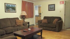 A living room with two couches, a coffee table, and a lamp. There are two framed pictures on the walls.