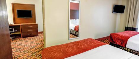 A hotel room with two beds, a desk with a chair, a television, and a mirror.