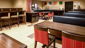 A hotel lobby with a bar area, seating, and a kitchenette. - Charlotte Suites (Charlotte)