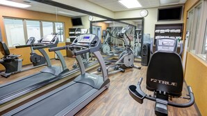 A gym with treadmills, ellipticals, and weight machines. - Charlotte Suites (Charlotte)