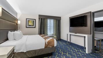 Una habitación de hotel con una cama grande, un televisor de pantalla plana, un escritorio y una ventana con cortinas.