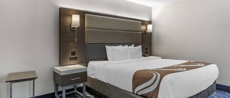 A hotel room with a large bed, a bedside table, and a nightstand.