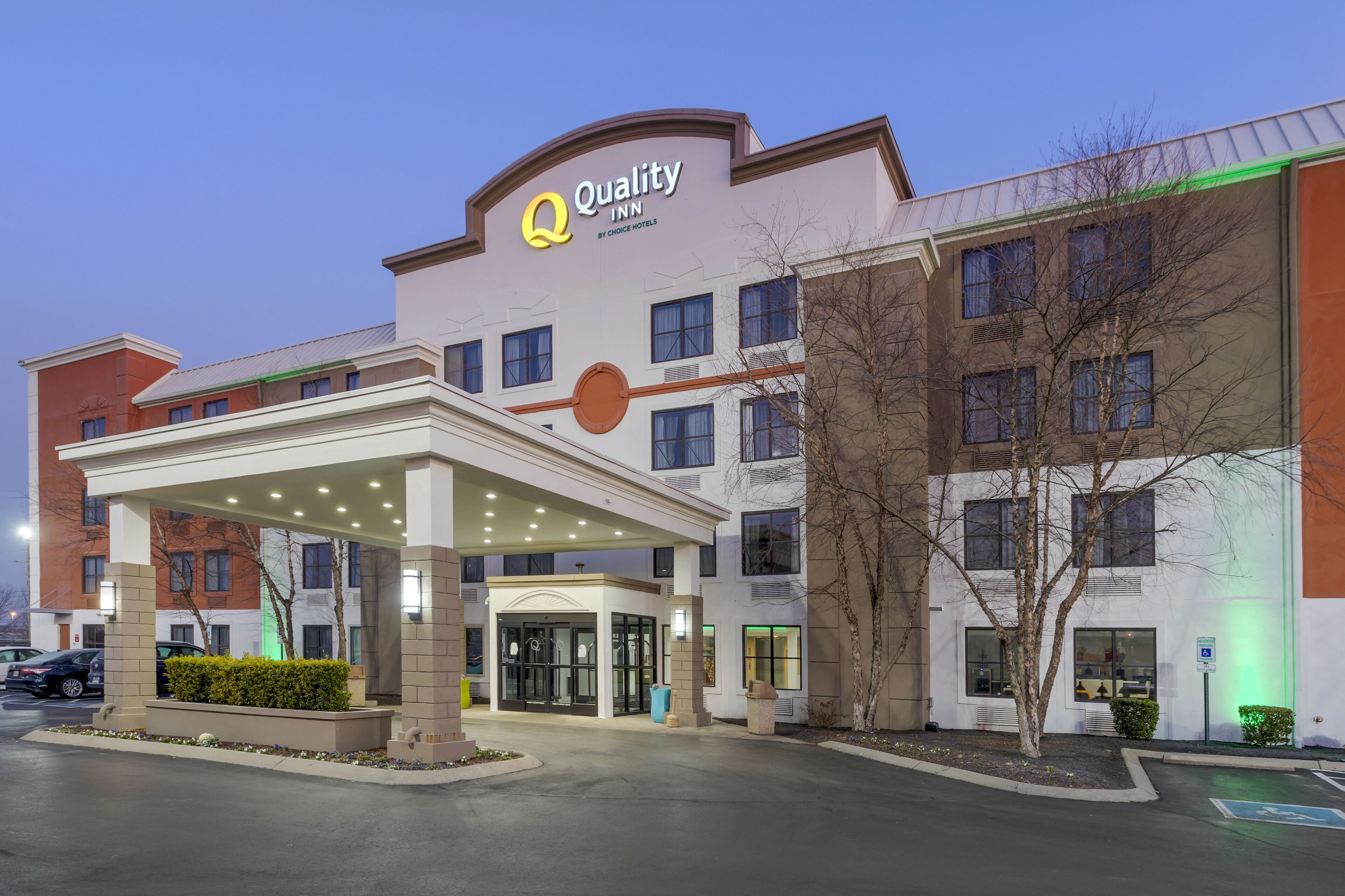 L’entrée d’un hôtel, dotée d’un espace abrité, de nombreuses fenêtres et d’une enseigne indiquant « Quality Inn by Choice Hotels ».