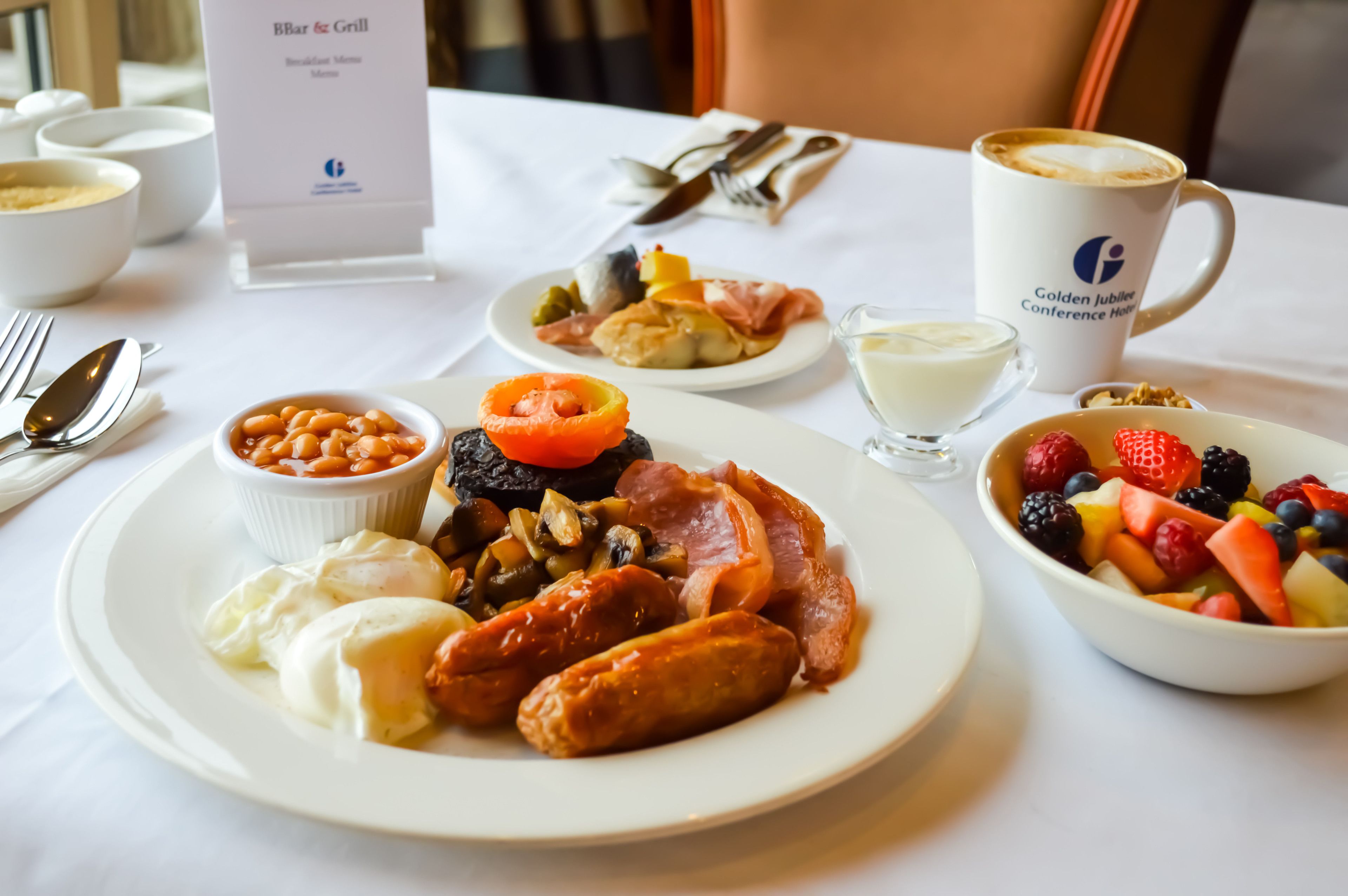 A breakfast setting with plates of food, a coffee cup, and a menu sign.