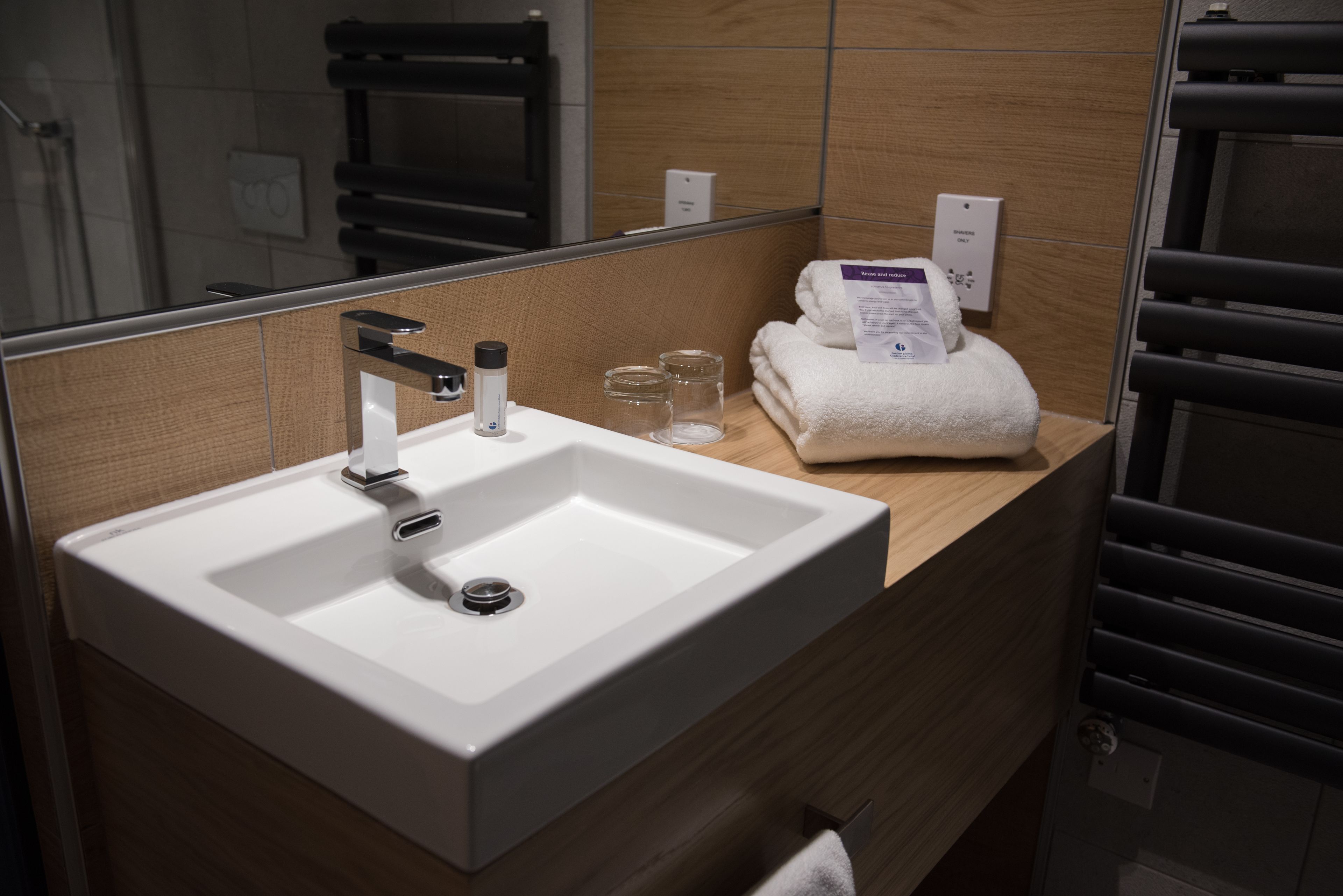 A modern bathroom with a large sink, a mirror, and a towel rack.