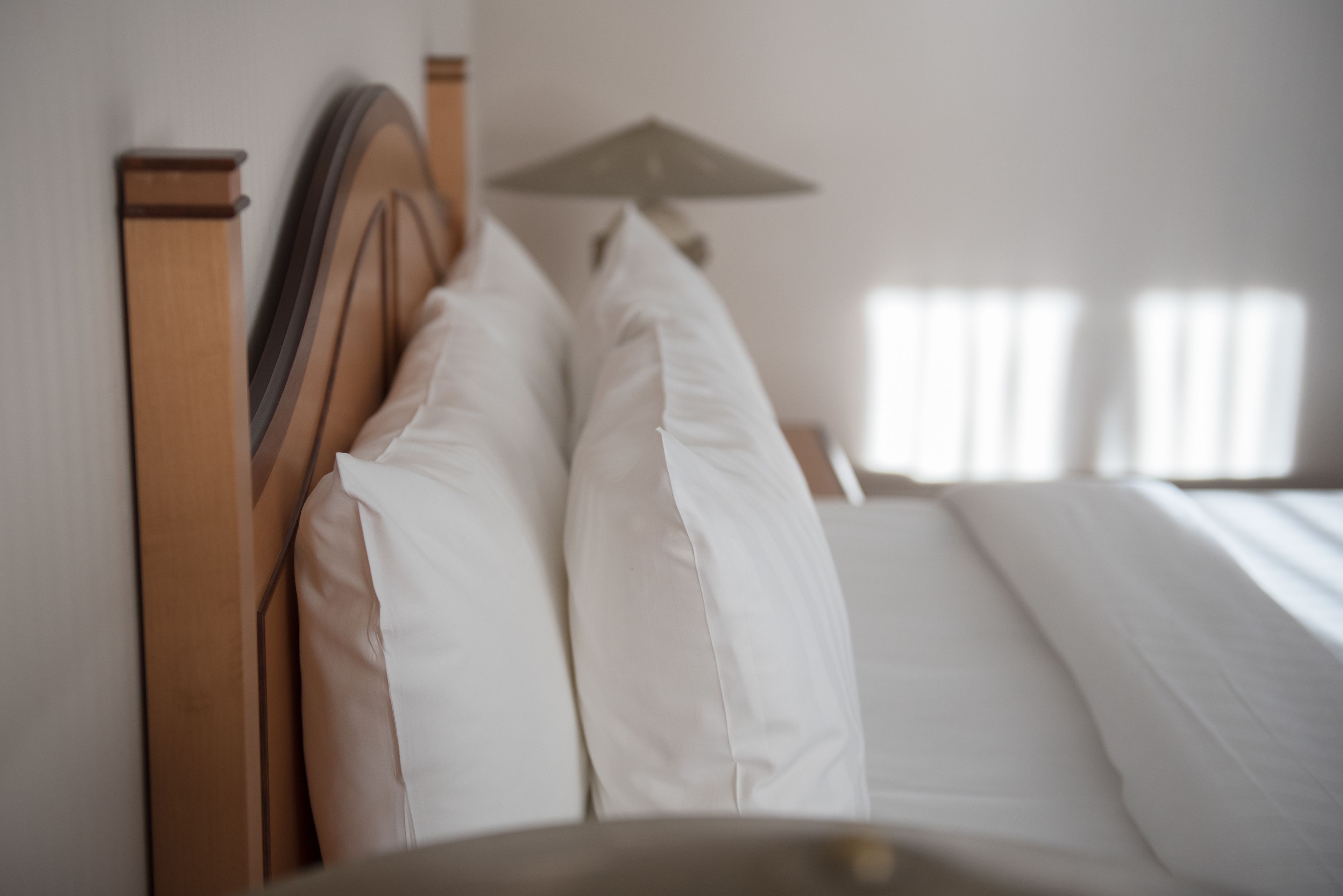 A bed with white linens and a wooden headboard.
