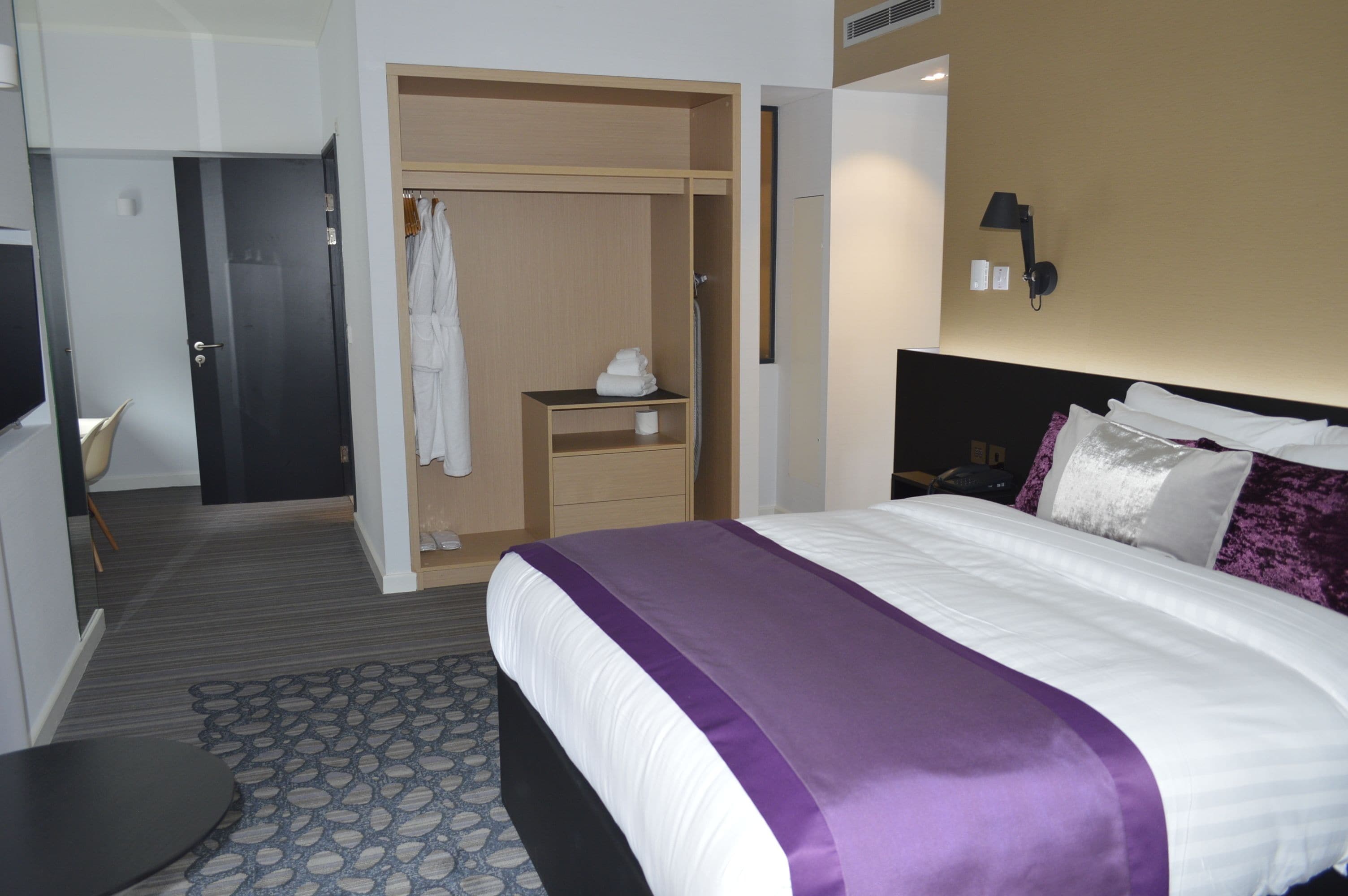 Habitación de hotel con cama, armario, escritorio y baño.
