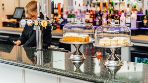 A bar counter with two glass-covered dessert displays and a bartender. - Golden Jubilee Hotel (Clydebank)
