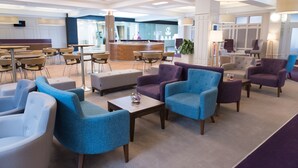 A modern hotel lobby with seating areas, a reception desk, and a large window. - Golden Jubilee Hotel (Clydebank)