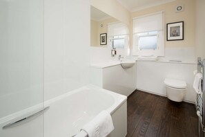 A modern bathroom with a bathtub, sink, and toilet.