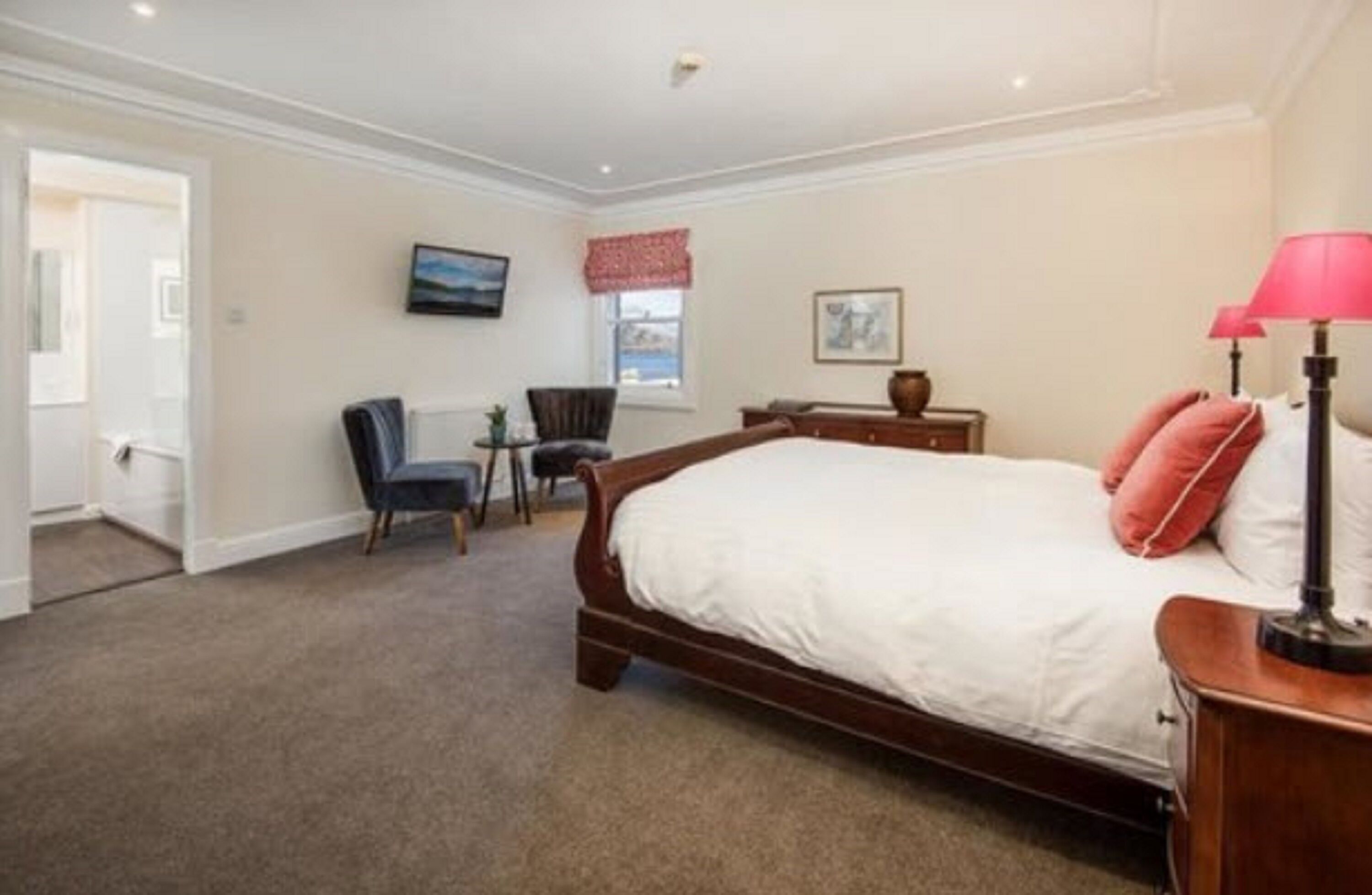 A bedroom with a large bed, a desk, a chair, and a window with a view.