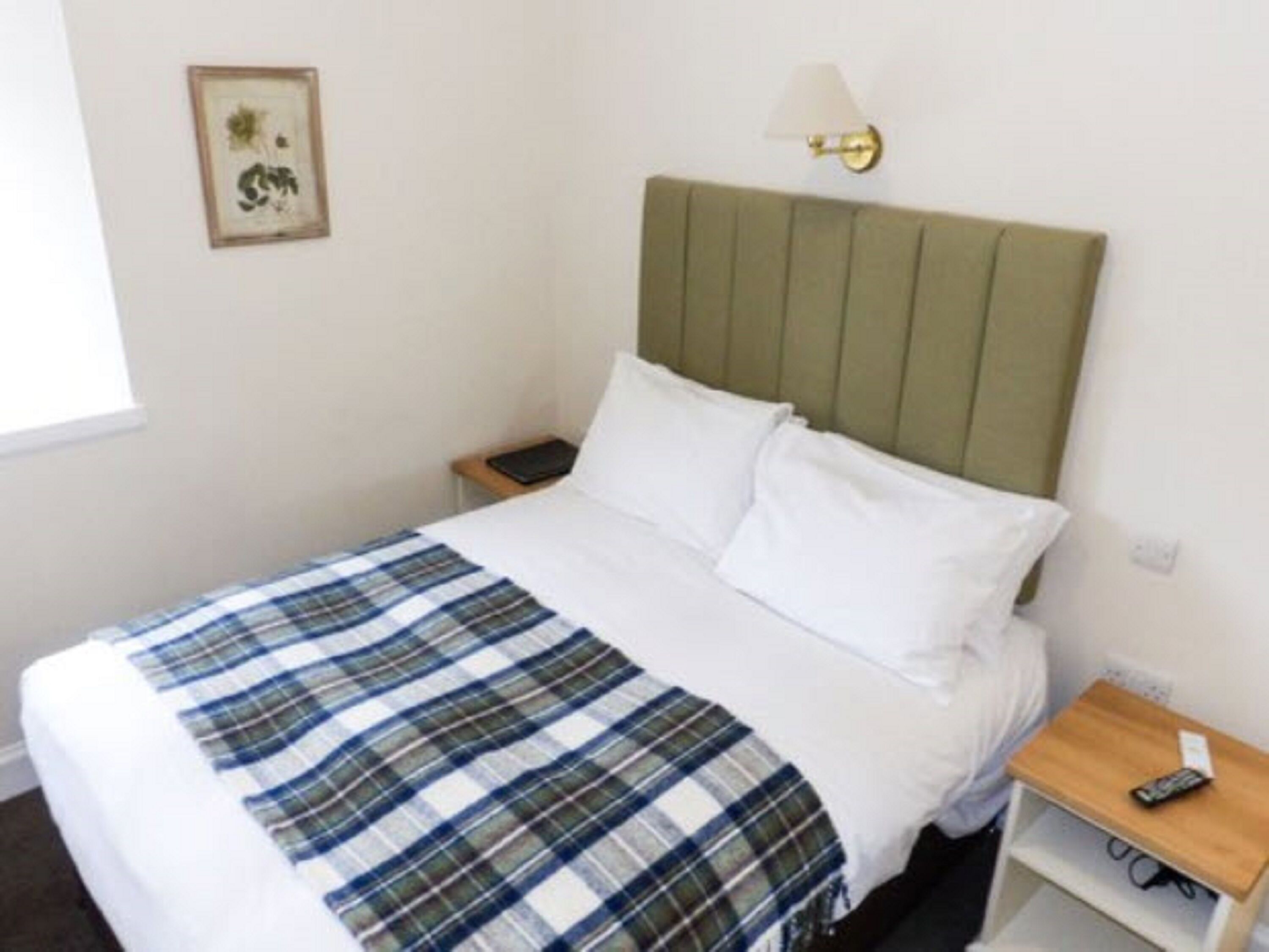 Une chambre d’hôtel avec un lit, une table de chevet, une lampe et un tableau encadré au mur.