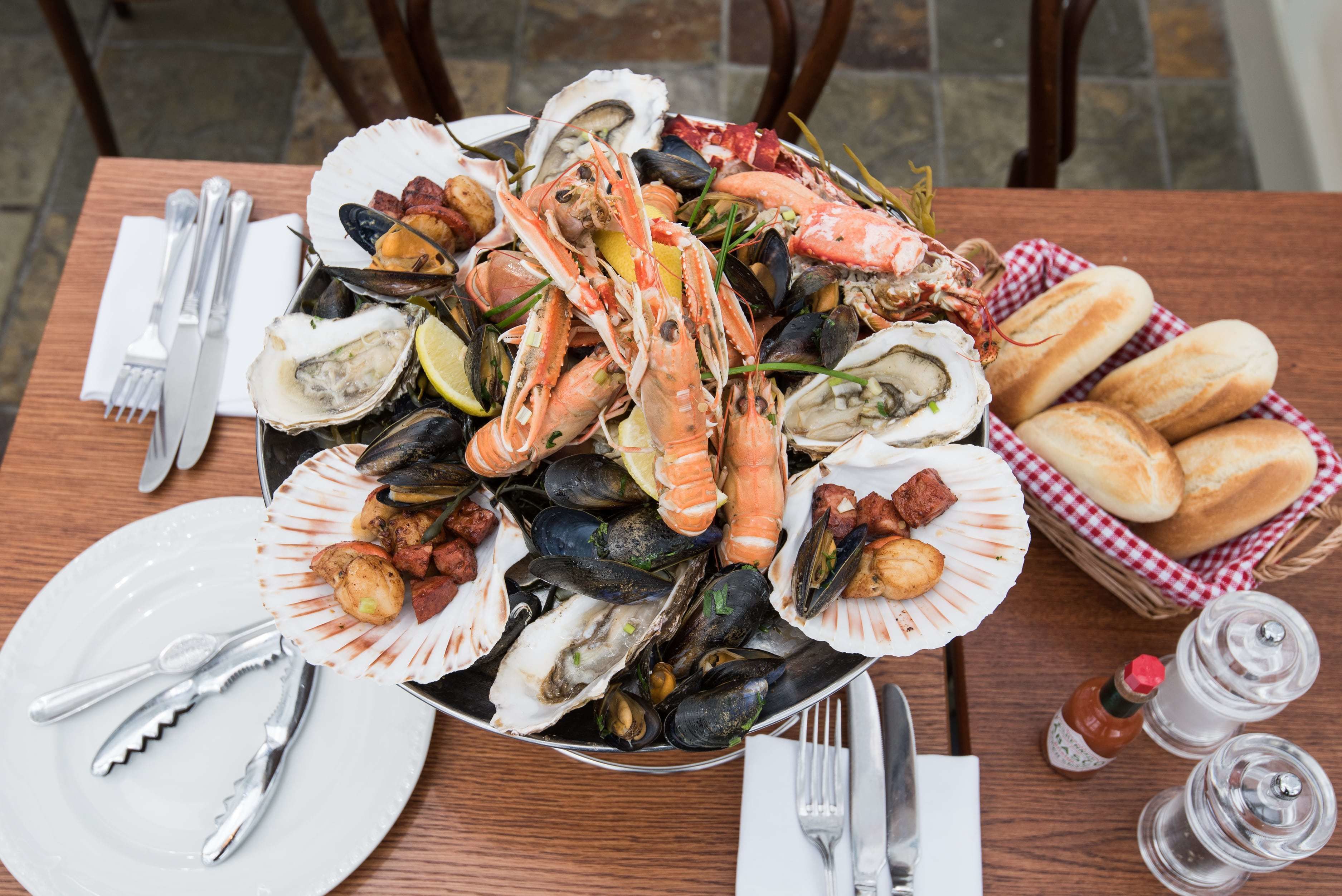 A seafood platter with various shellfish and bread on a wooden table.