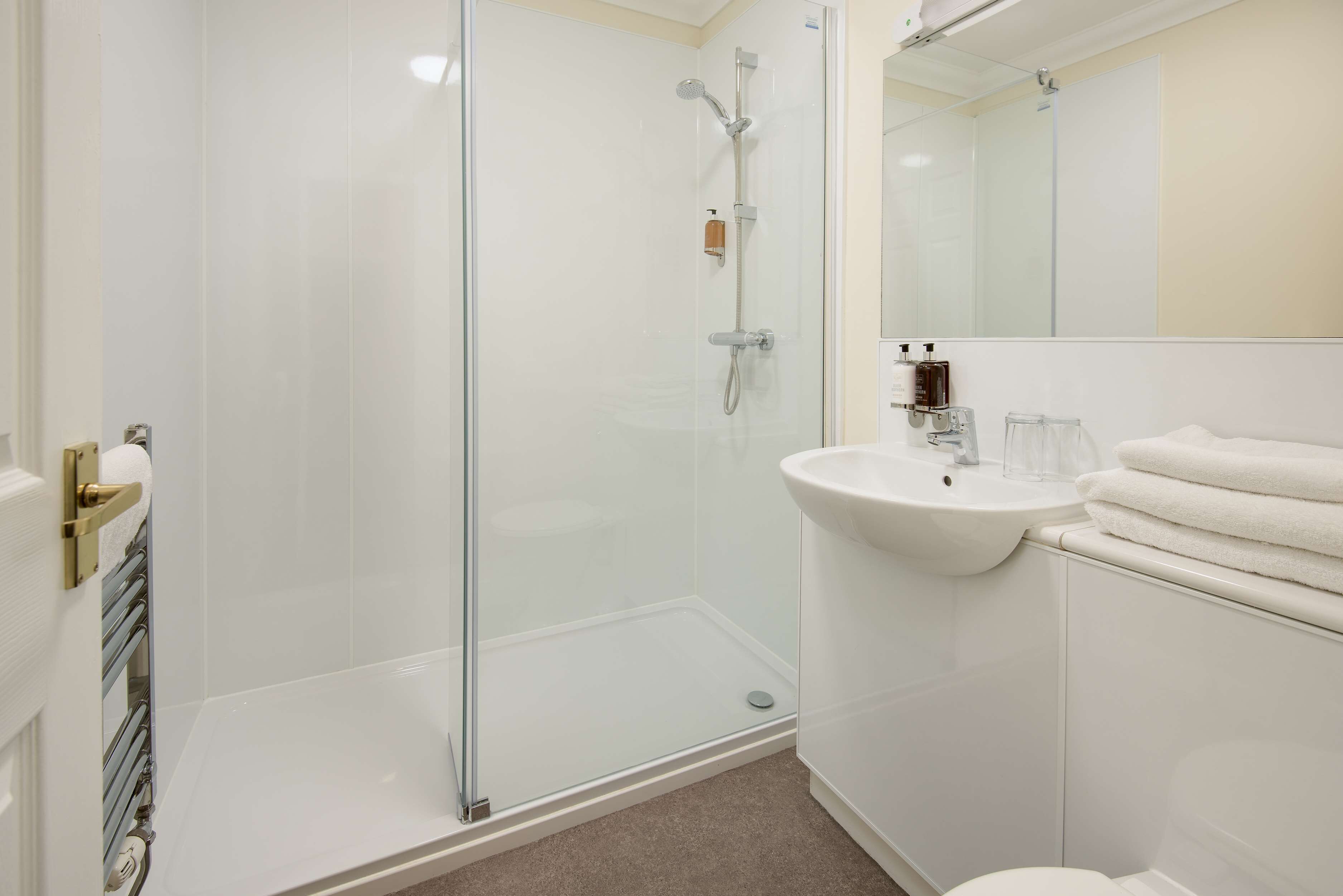 Une salle de bain moderne avec une douche à parois de verre, un lavabo blanc et des toilettes.