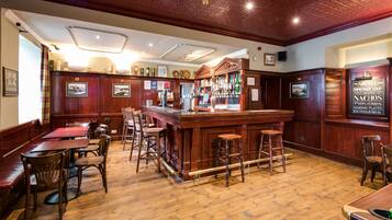 A bar area with wooden furniture, a bar counter, and various signs and decorations.