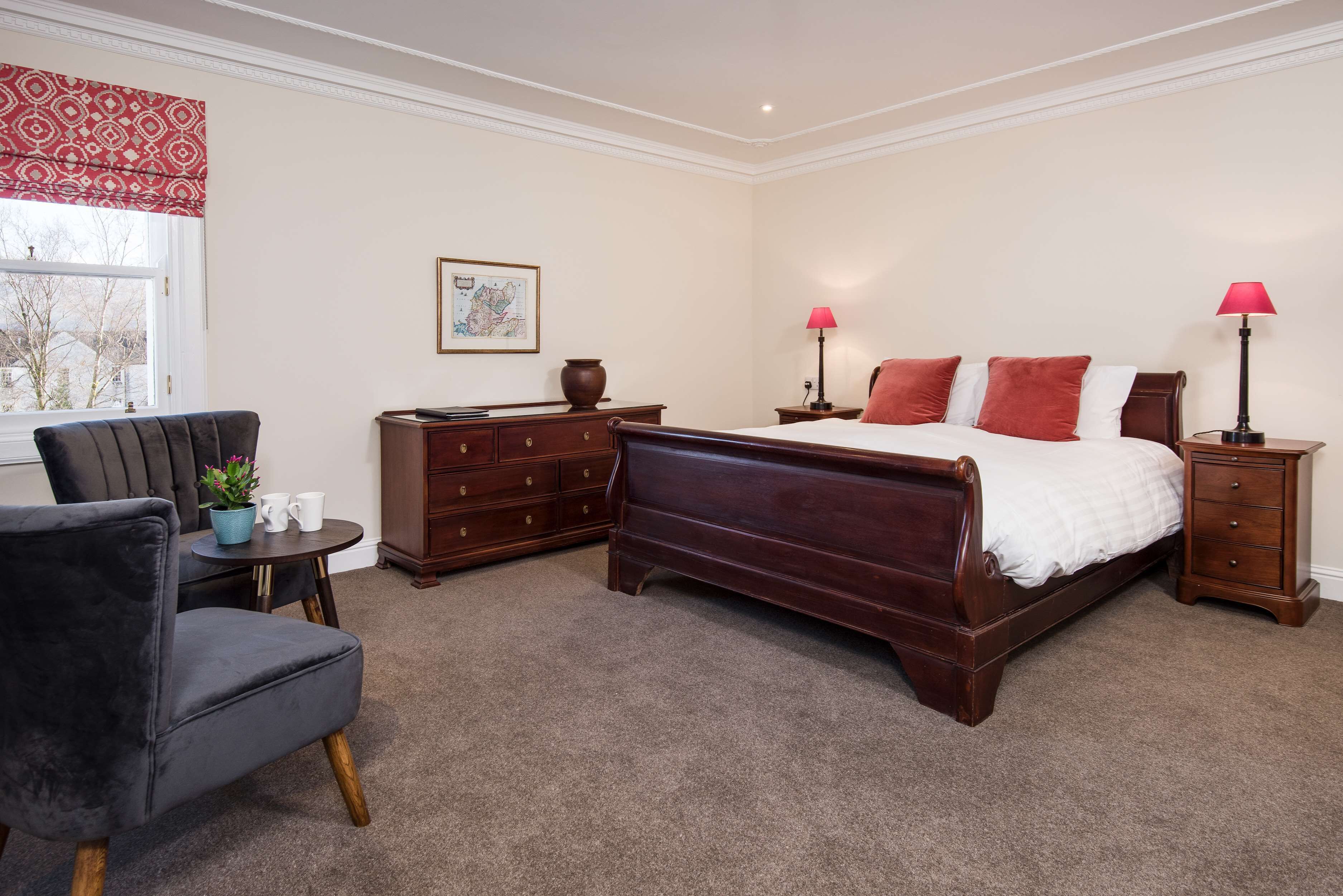 A bedroom with a large bed, a chair, a dresser, and a nightstand.