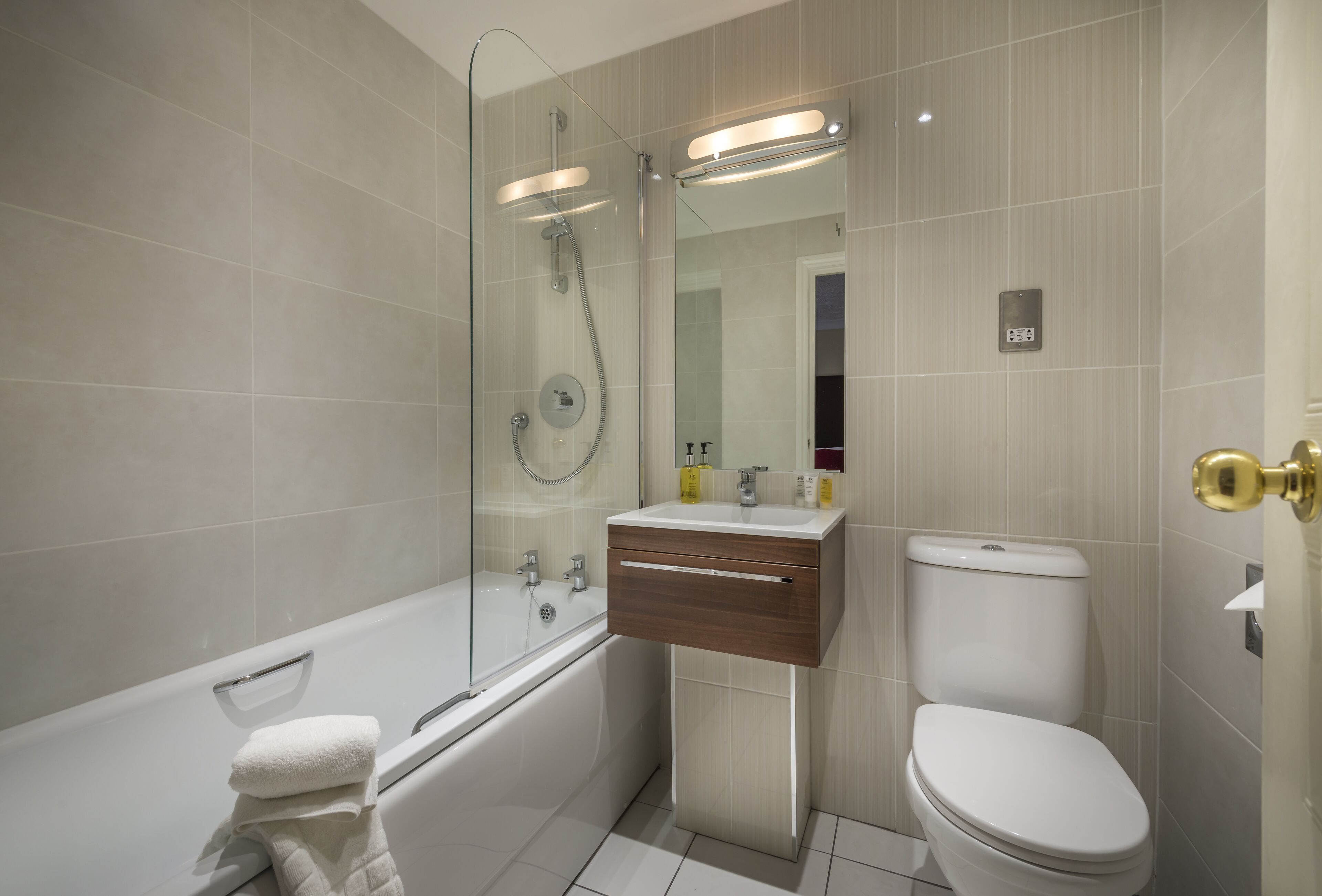 Ein modernes Badezimmer mit einer Duschkabine, einer weißen Badewanne, einem Waschtisch mit Spiegel und einer Toilette.