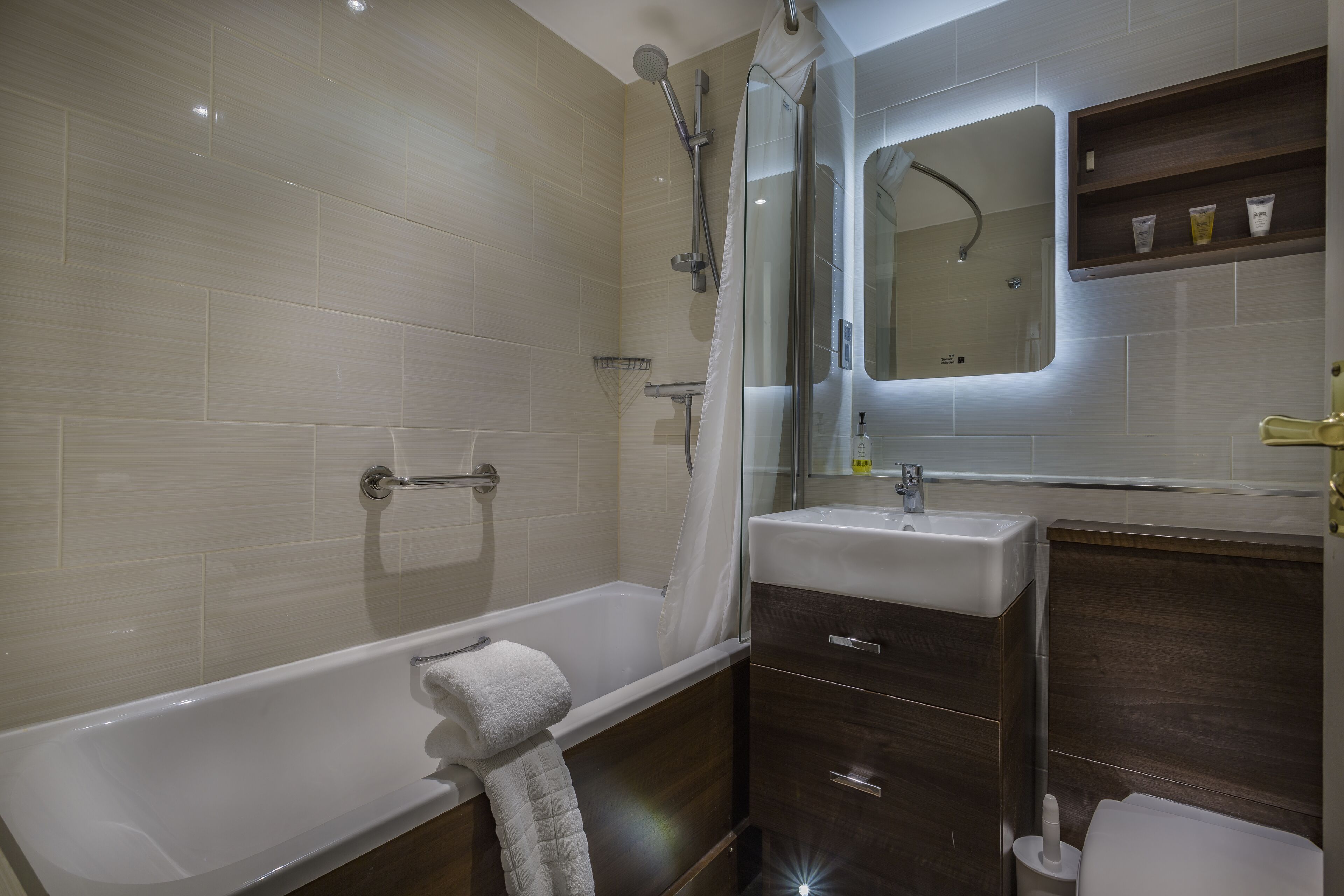 Ein modernes Badezimmer mit Badewanne, Dusche, Waschtisch mit Spiegel und Toilette.