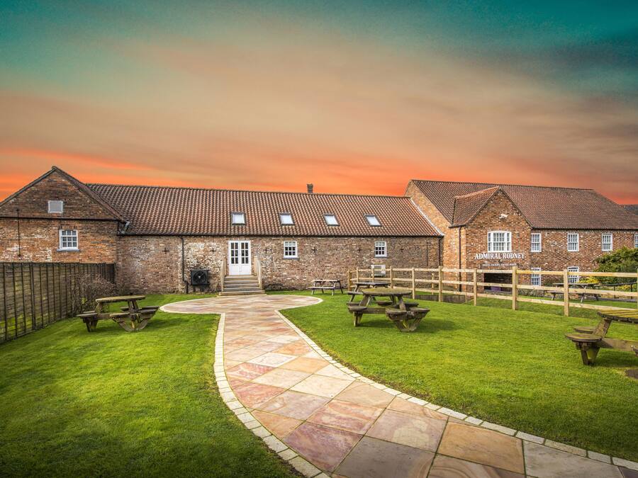 A brick building with a stone pathway leading to a wooden fence.