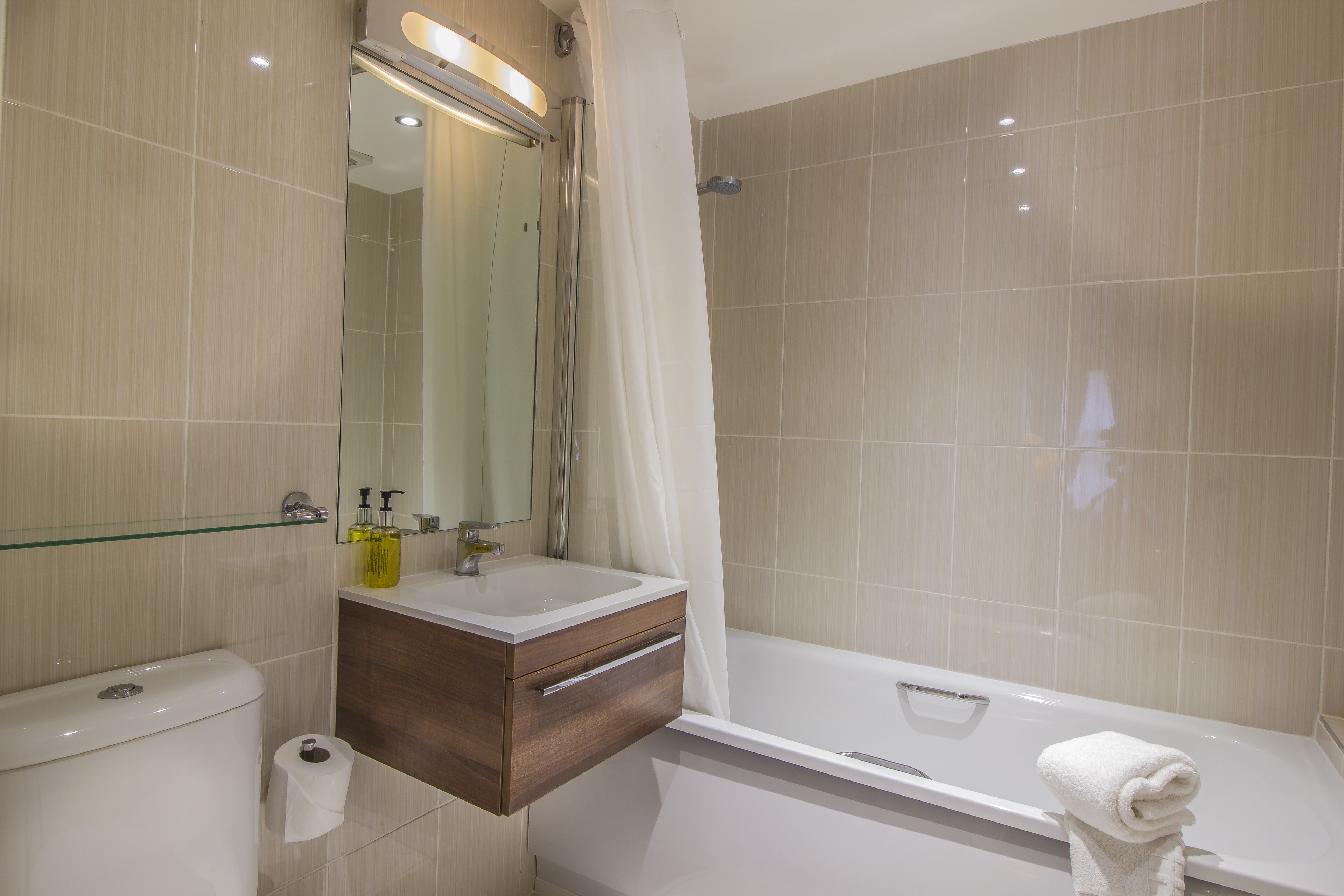 Ein modernes Badezimmer mit Toilette, Waschbecken, Waschtisch und Badewanne.