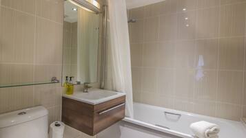 A modern bathroom with a toilet, sink, vanity, and a bathtub.