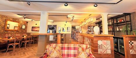 A hotel lobby with a bar area, seating arrangements, and a fireplace.