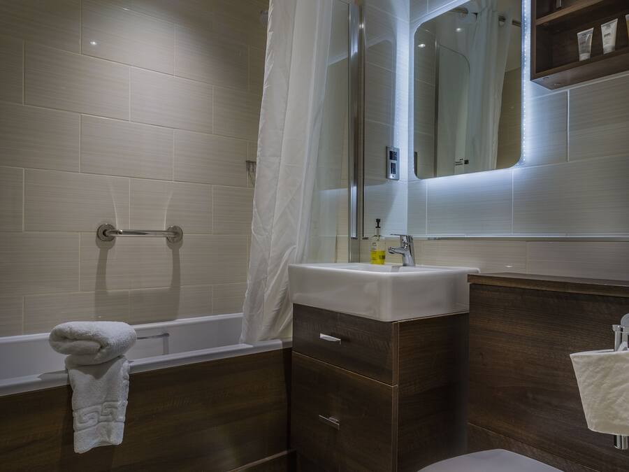 Een moderne badkamer met een bad, toilet en een wastafel met spiegel.