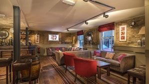 A cozy bar area with stools, a sofa, and a bar counter. - The Admiral Rodney Hotel, Horncastle, Lincolnshire (Horncastle)