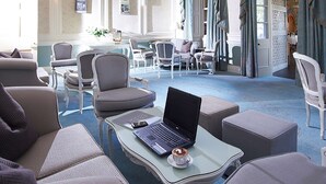 Amplia habitación con candelabro, zona de estar y un ordenador portátil sobre una mesa.