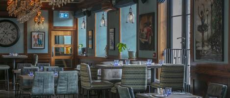 Un restaurante con vigas de madera, candelabros y cuadros enmarcados en las paredes.