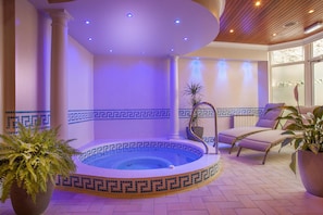 Un área de spa con una bañera de hidromasaje, sillas de descanso y plantas en macetas.