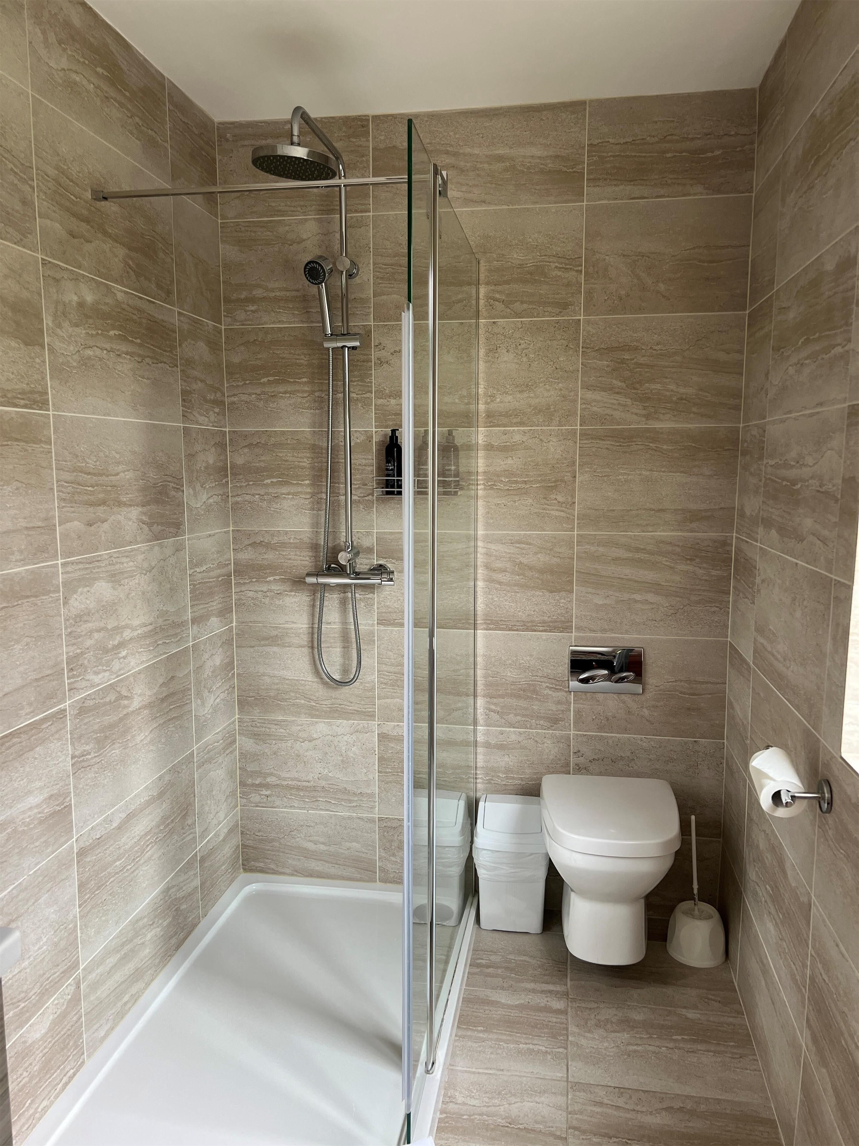 A modern bathroom with a glass-enclosed shower, a toilet, and a bidet.