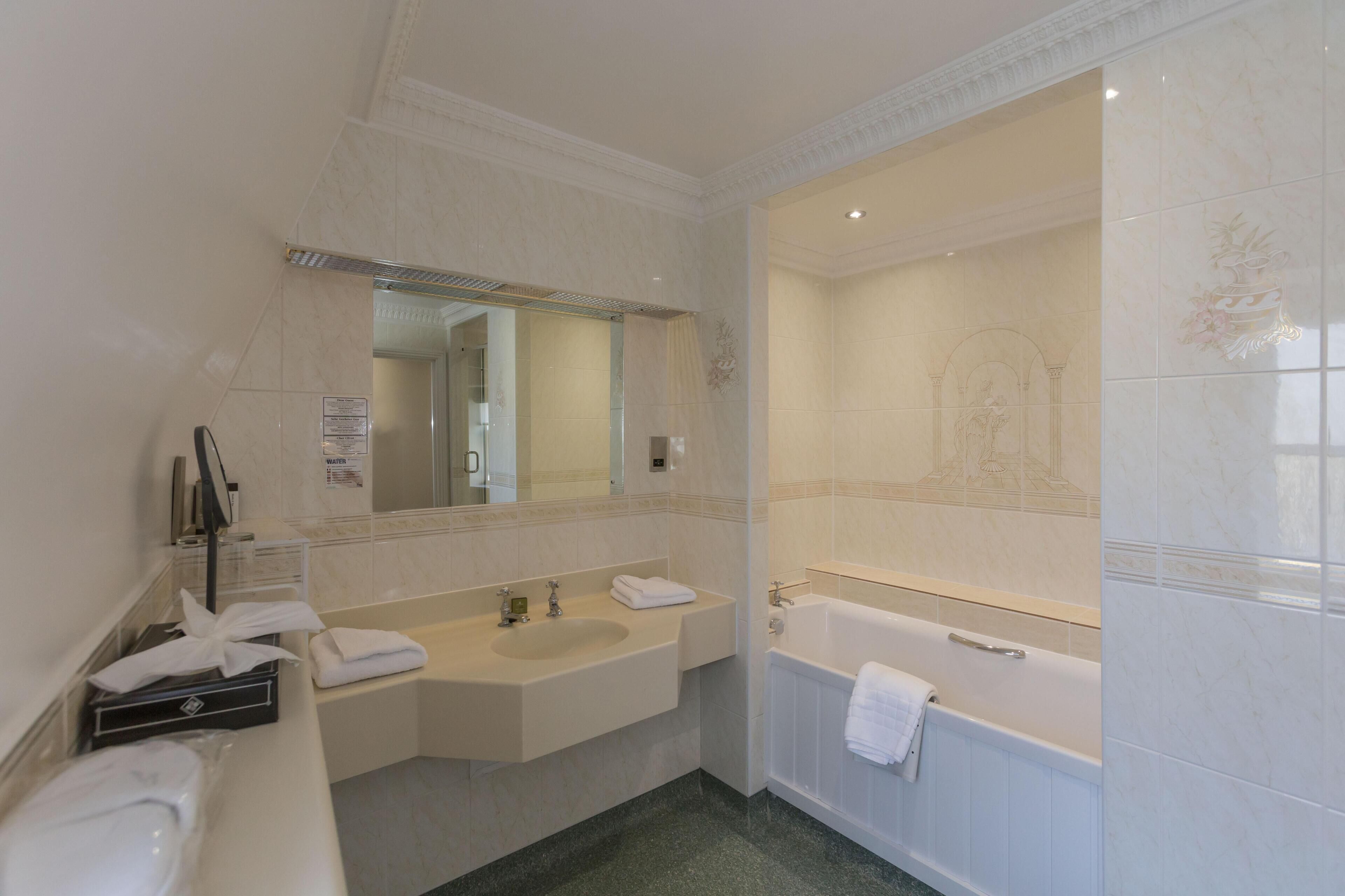 A bathroom with a sink, mirror, and bathtub.