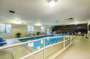 Un área de piscina con una piscina cristalina, sillas de descanso blancas y un ventilador de techo.