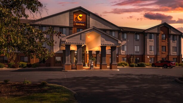 Un hôtel reconnaissable à son grand panneau « Comfort Suites », une entrée abritée par des colonnes et un parking.
