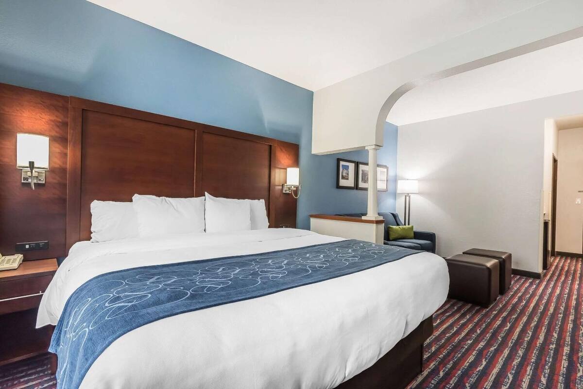 Ein Hotelzimmer mit einem großen Bett, einem Schreibtisch, einem Stuhl und einer Lampe.