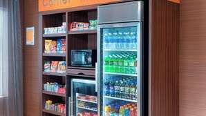 A corner market with shelves stocked with snacks, beverages, and a microwave. - Fairfield Inn and Suites By Marriott St Charles (St. Charles)