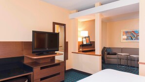 A hotel room with a bed, a TV on a wooden stand, a small desk with drawers, a sofa, two side tables, and a lamp. - Fairfield Inn and Suites By Marriott St Charles (St. Charles)