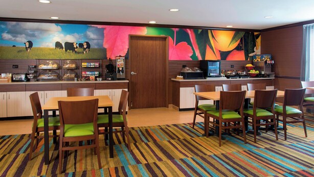 A hotel room with a breakfast bar, a large mural, and a carpeted floor. - Fairfield Inn and Suites By Marriott St Charles (St. Charles)